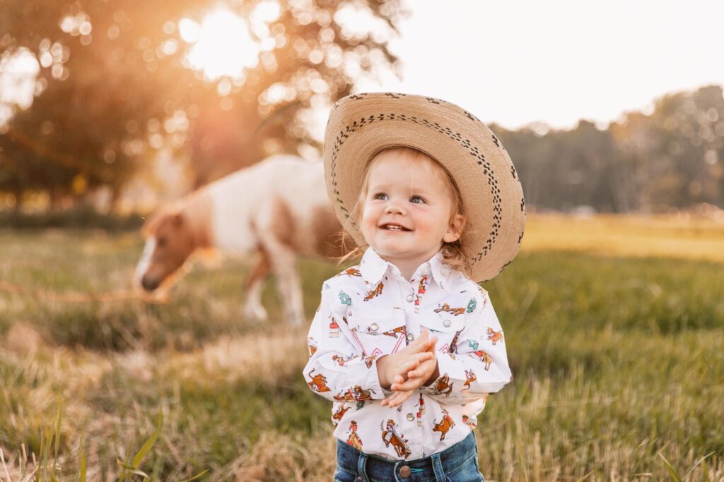 Image of toddler in a field with mini horse